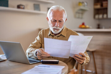 Planning, documents and finance with elderly man on laptop in a kitchen, reading retirement and savings plan in his home. thinking, mortgage and investment paperwork with retired male contemplating.