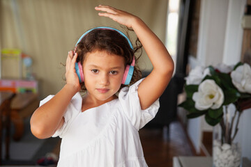 Concentrated girl listening with headphones music at home - obrazy, fototapety, plakaty