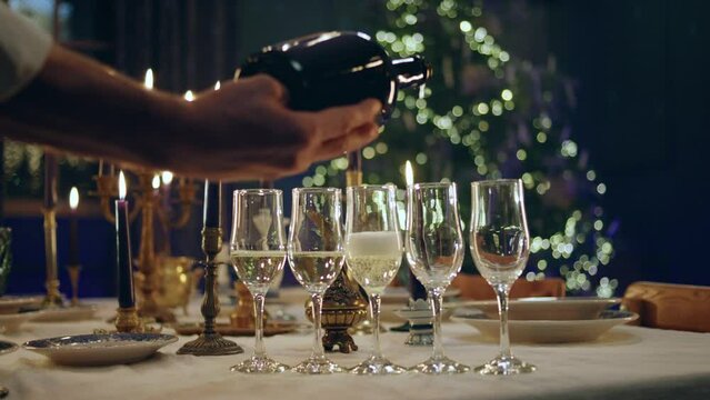 Closeup to the camera on the Christmas dining table capturing video details someone pour some sparkling wine on the glasses amazing Christmas atmosphere around