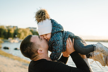 Dad kiss daughter walking in park. Father throws up child, flying into sky near lake in nature....