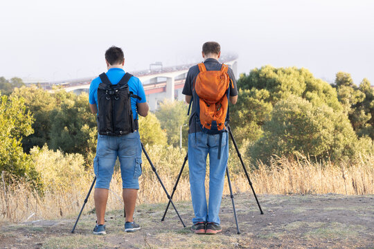 Two photographers take pictures of the bridge standing on the hill