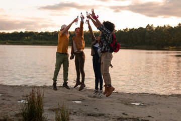 group of friends celebrating freedom on the bank river at sunset