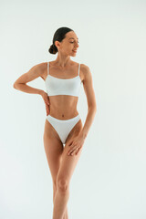 Naklejka premium Front view. Young woman with slim body type is in fitness clothes in the studio
