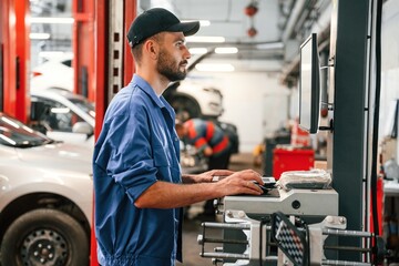 Standing by computer terminal. Auto mechanic working in garage. Repair service