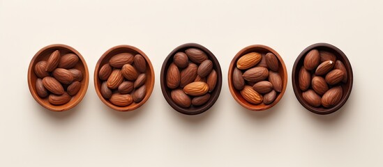 Five sweet brown chocolate cinnamon almonds in small wooden bowl on a isolated pastel background...