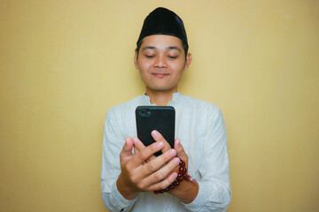 an Indonesian Muslim man of Asian descent wearing Muslim clothes and a black peci, celebrating Eid...