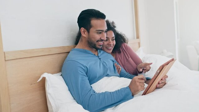 Tablet, laughing and couple in bed networking on social media, mobile app or the internet. Happy, funny and young man and woman relax and scroll on website with digital technology in bedroom at home.