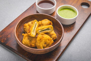 Paneer Pakoda with sweet and tangy chutney on a wooden plate, served hot