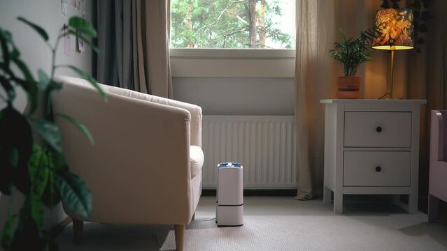 Modern air humidifier in action in living room. Contemporary smart humidifier in bedroom emitting water vapor and moisturizing air in cozy room