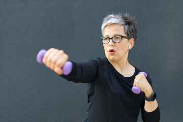 A mature Caucasian woman, radiating health and beauty, exercises outdoors, displaying strength and...