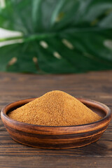 Unrefined cane sugar Panela in a clay bowl with a monstera leaf.