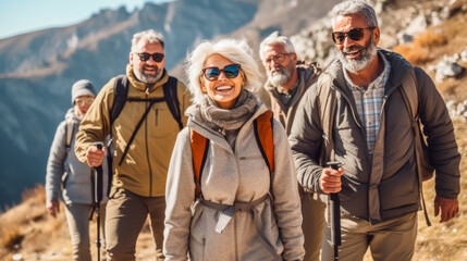Group of senior travelers and elderly friends hiking in the mountains smiling and having fun in the amazing trekking and looking at the camera together. concept of living outdoor adventure style - obrazy, fototapety, plakaty