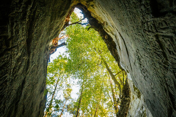 Urban Cavern Dark Entrance to a City Tunnel Amidst Nature's Landscape. Entrancing rock tunnel with architectural doorway; natural light and water create serene atmosphere.