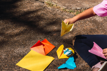 Girl playing with a paper airplane in a park and making more origami figures