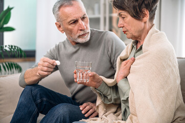 Mature unhealthy, ill woman taking medication from high temperature