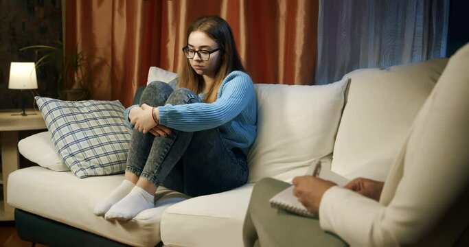 Teenage girl, a high school student, attending a psychological counseling session with the psychologist. The distressed girl finds it challenging to articulate her issues, not speaking for a long time