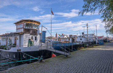 Old tug boat, sailing ships at the pier Södermälarstrand, cumulus clouds, a sunny autumn day in...