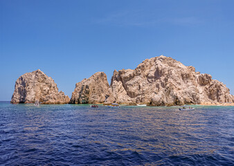 Mexico, Cabo San Lucas - July 16, 2023: Reserva de Lobos Marinos landsend between ocean and Playa de los Amantes, lovers beach under blue sky. Small sightseeing boats in front