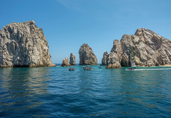 Fototapeta na wymiar Mexico, Cabo San Lucas - July 16, 2023: Reserva de Lobos Marinos channel between boulders linking ocean with bay under blue sky. Small sightseeing boats in front