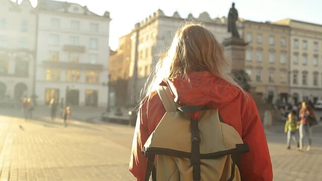 Real view of traveller woman walking on old Market Square in Krakow holding tourist map. Travel and active lifestyle concept. High quality photo. High quality FullHD footage