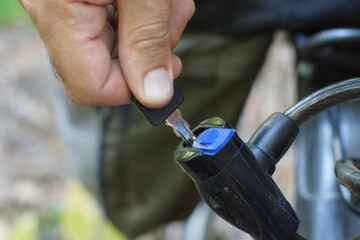 a man's hand with the help of an iron new key opens a reliable safe metal in a plastic black tube...
