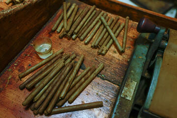 Close up of dried tobacco leaves and fresh hand rolled premium cuban cigars in the factory. The art...