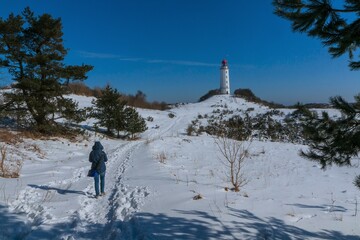 Back view of a woman walking along the Dornbusch lighthouse on the island of Hiddensee in winter.