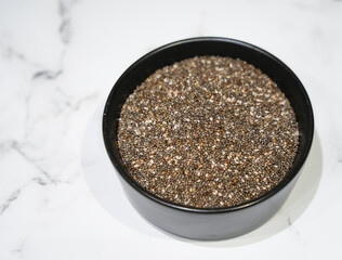 Chia Seeds in a Bowl on Marble Background.  Chia seeds, a nutritional powerhouse, are featured in this image. Rich in omega-3 fatty acids, fiber, and protein, these tiny seeds support heart health