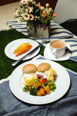 Egg Benedict slider with vegetable salad include tomato, potato, lettuce leaf and carrot with tea,...