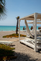 typical tropical atmosphere, beach holiday relax during sunny day in coastal resort with palm trees, baldaquin, deckchairs and ocean in the back, nobody © jan_S