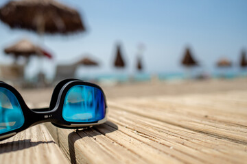 Fototapeta na wymiar swimming glasses laying on a blanket during hot summer day with blurred background, holiday and travel concept