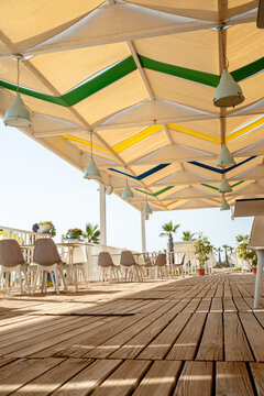 Empty wooden tables and chairs with no people in open restaurant bar on a tropical beach