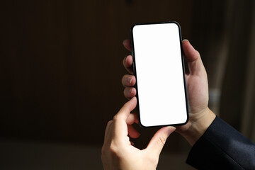 Close-up of male hand holding smartphone with white mockup on screen