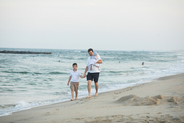 Fototapeta na wymiar Father and child playing on tropical beach at sunset. Family summer vacation at sea resort. Dad playing with kids on sunny evening at ocean shore. Travel with children. Parent love