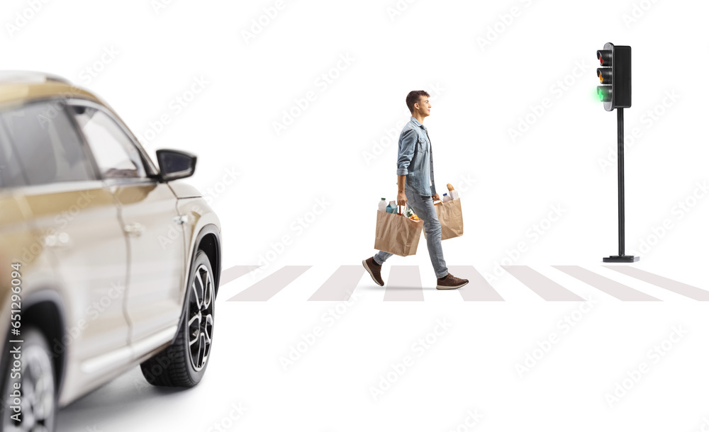 Poster Young man carrying grocery bags and crossing a street at pedestrian