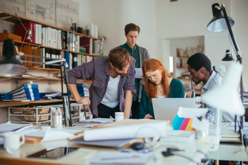 Young and diverse group of architects using a laptop and working together in a startup company office
