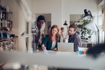 Young and diverse group of architects using a laptop and working together in a startup company office