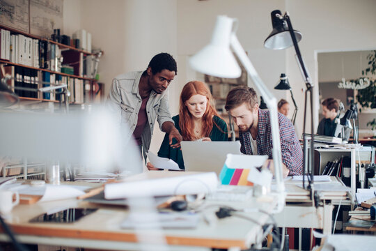 Young and diverse group of architects using a laptop and working together in a startup company office