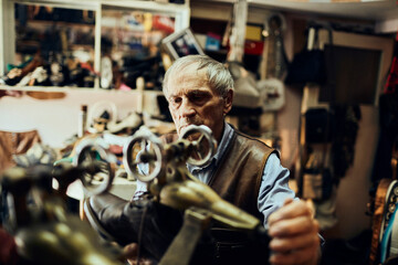 Senior male shoemaker restoring a shoe in his old workshop in the city