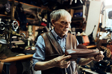 Senior male shoemaker restoring a shoe in his old workshop in the city