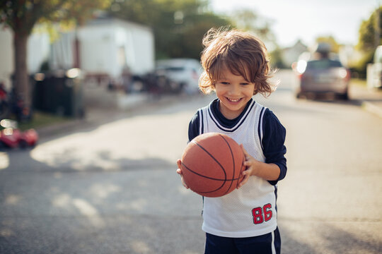 Portrait Of A Happy Young Caucasian Boy Holding A Basketball In The Street