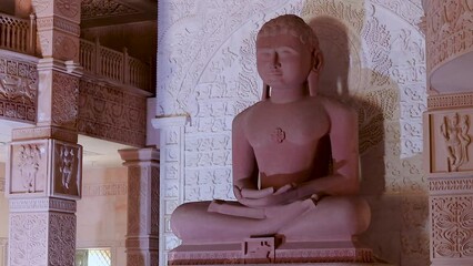 isolated red stone jain god holy statue in meditation from different angle