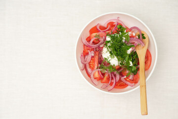 Salad of tomatoes, onions, sour scream and green in white plate on white background. Top view, health food.