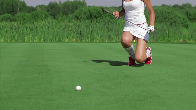 Woman kneels at the golf