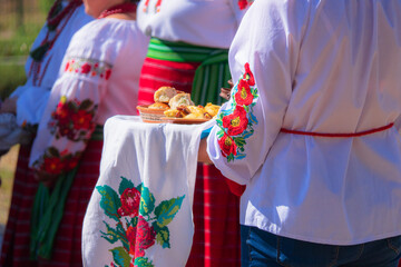 A Ukrainian woman holds food on an embroidered towel.