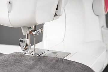 Modern sewing machine with gray fabric. Sewing process clothes, curtains upholstery. Business, hobby, handmade, zero waste, recycling, repair concept