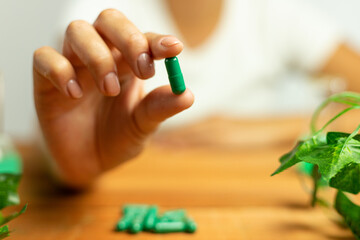 Natural laboratory, hands holding green pills, nature in medicine, herbal capsules, supplements, vitamins, minerals