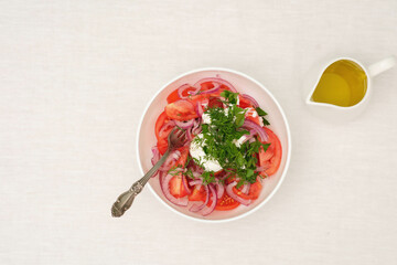 Salad of tomatoes, onions, sour scream and green in white plate on white background. Top view, health food.