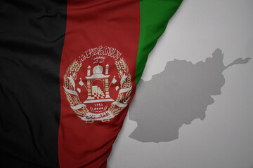 big waving national colorful flag and map of afghanistan on the gray background.