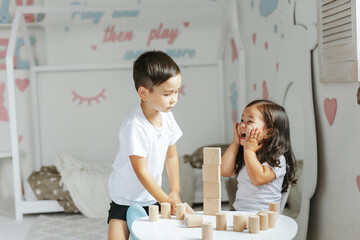 children boy and girl play with wooden toys at home in children's bedroom